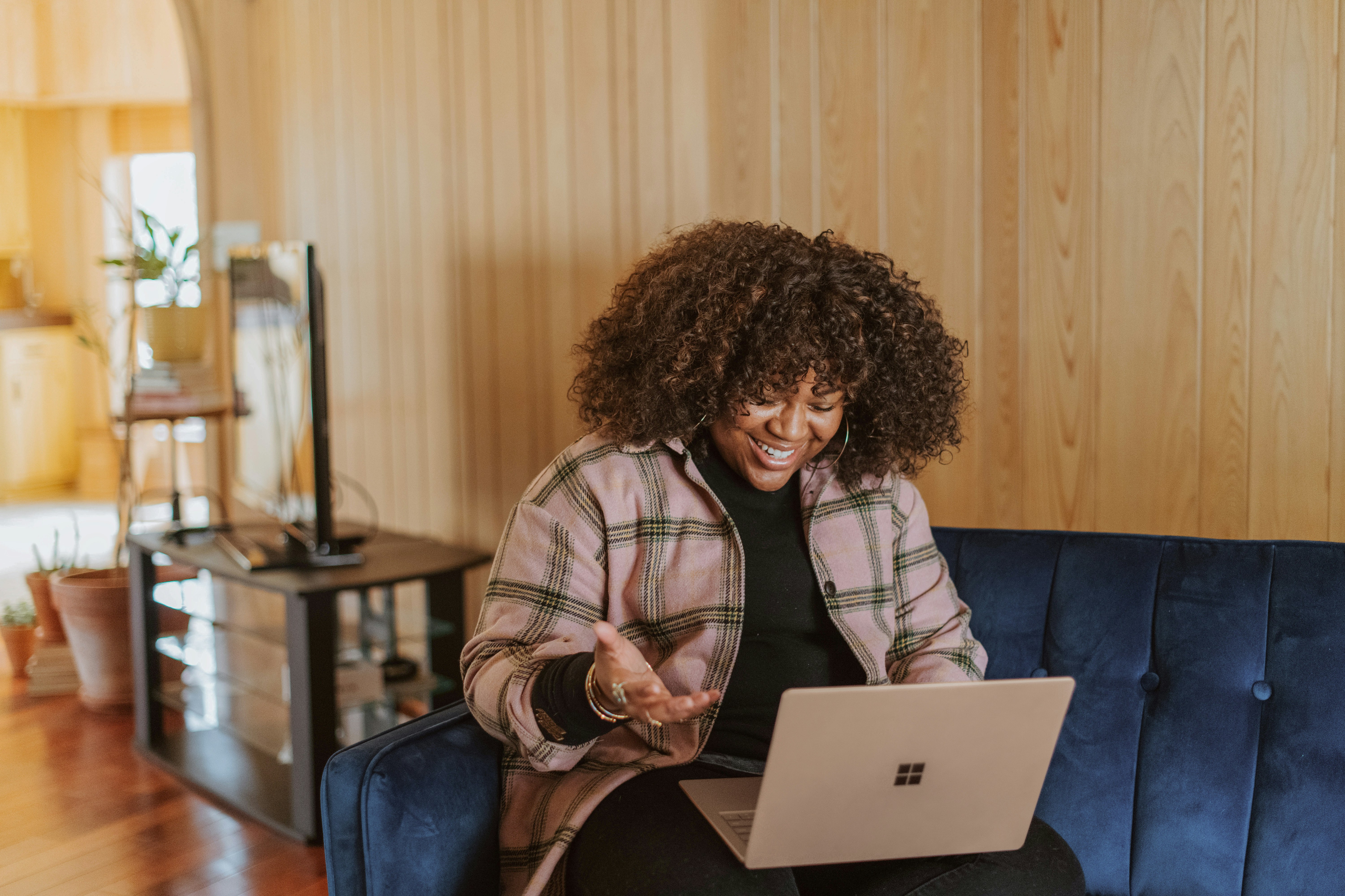 Woman smiling to laptop, which is balanced on knee 