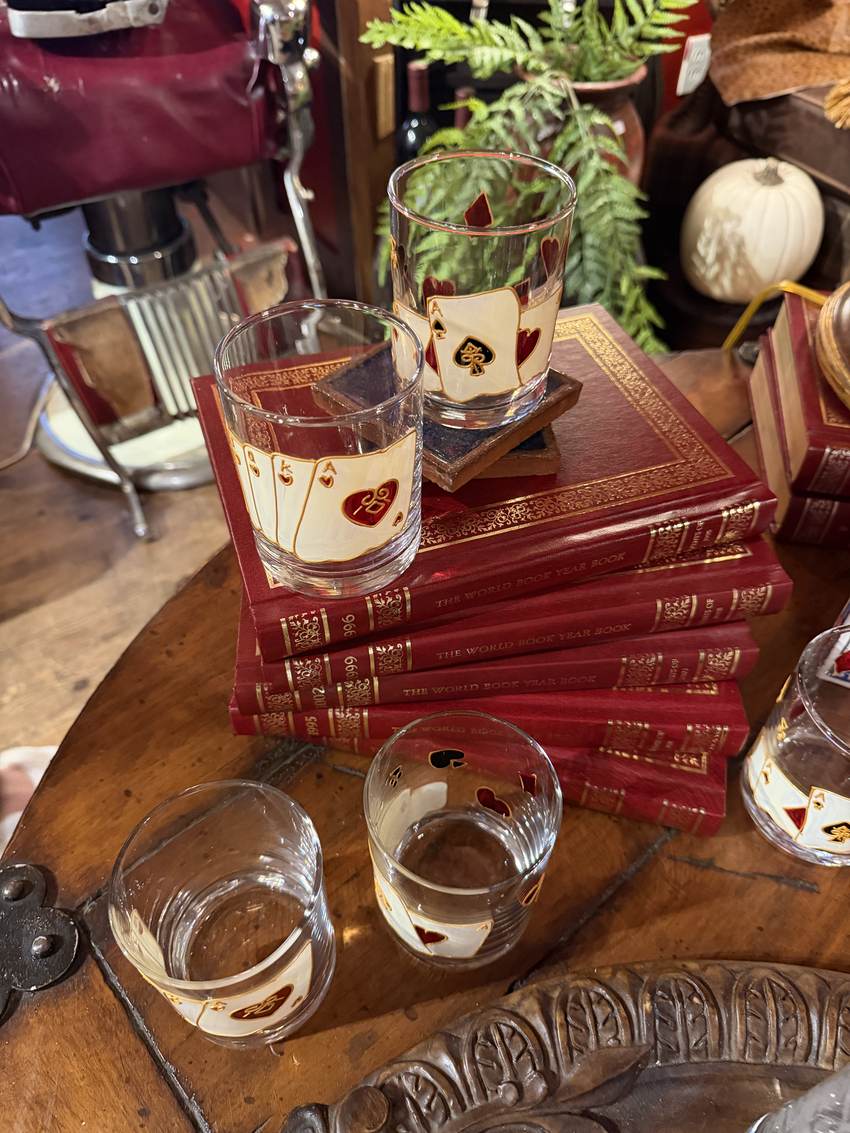Vintage playing card tumblers on a stack of leather bound books at Horse Feathers Mercantile