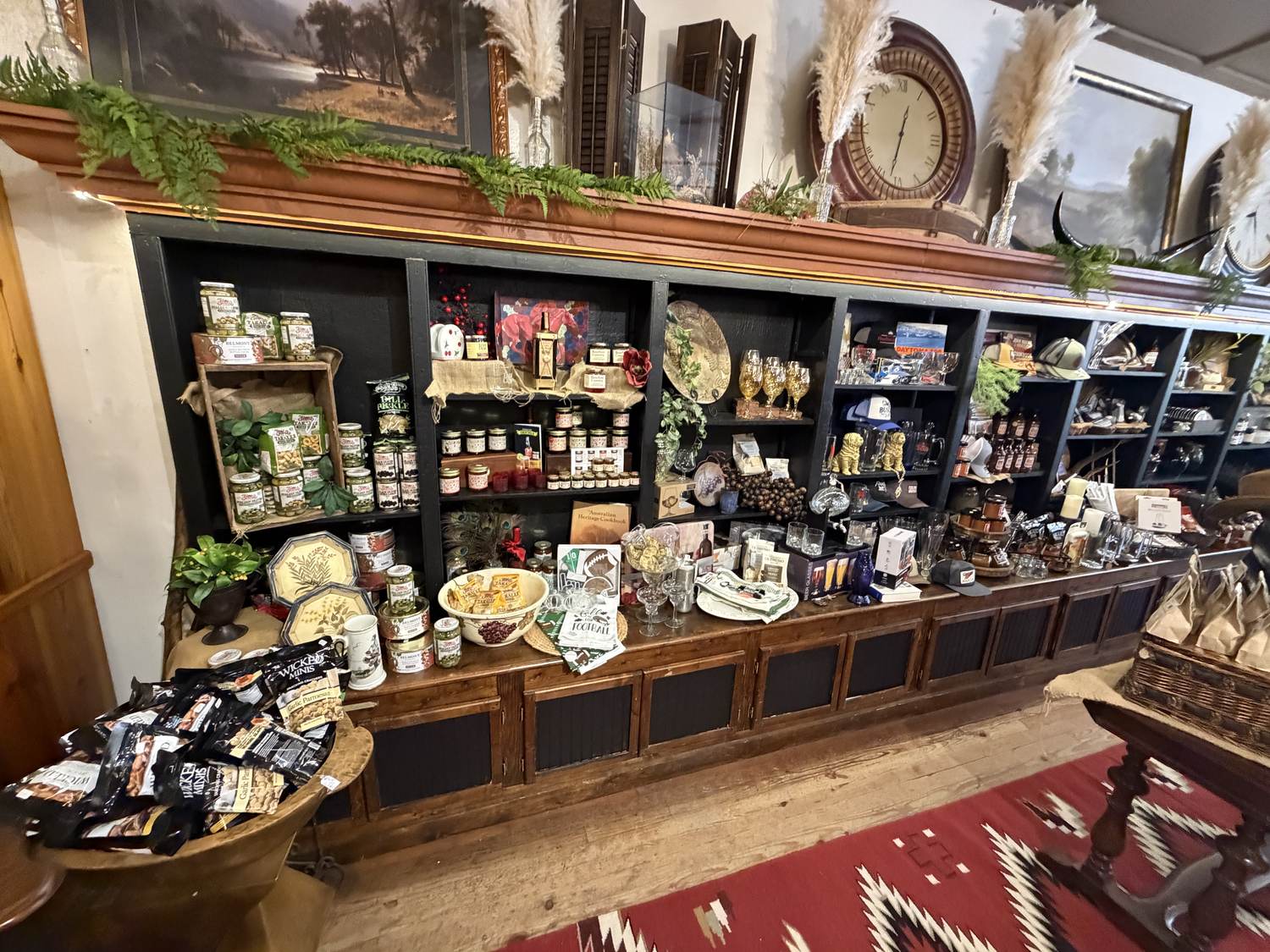 Olives, preserves, glassware and bar goods lining the long mercantile shelf at Horse Feathers Mercantile