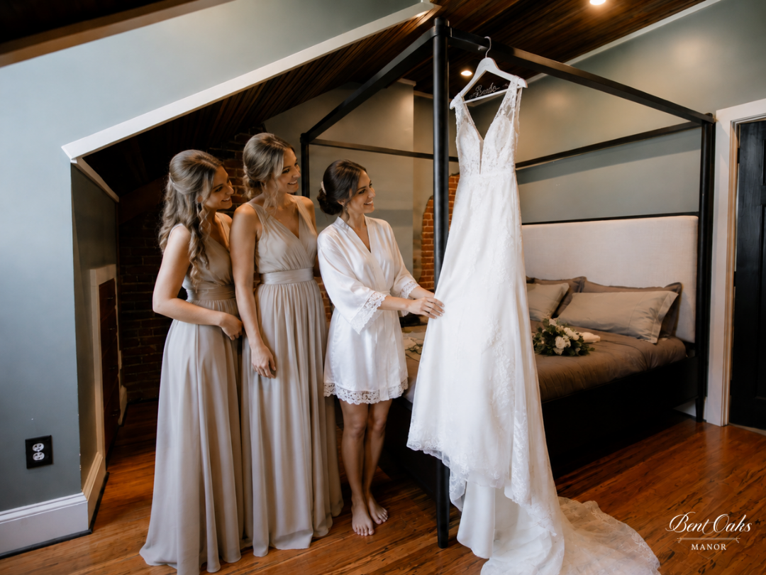 Bride and bridesmaids posing with wedding dress in bent oaks manor loft honeymoon suite