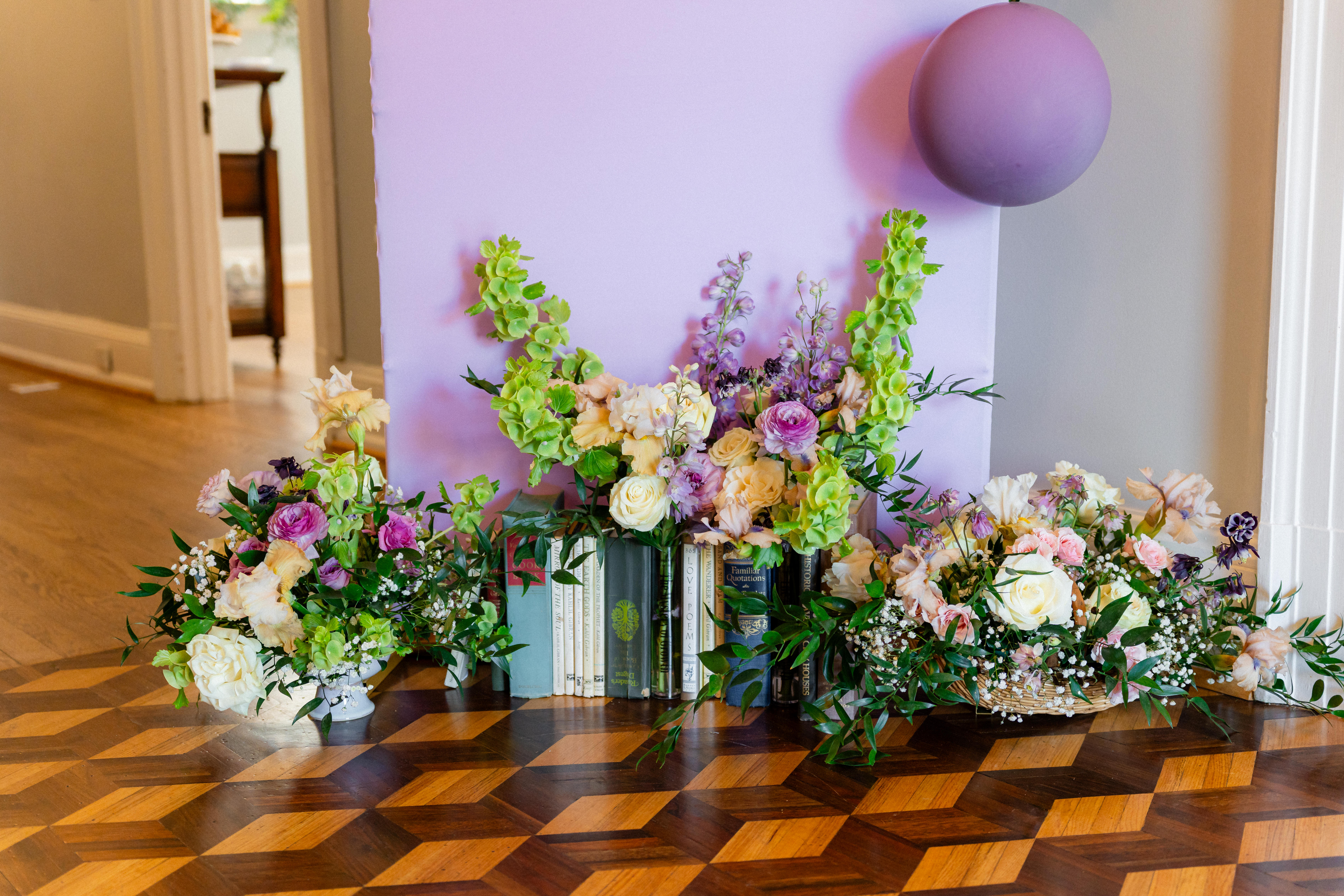 Pastel flowers and books beside a lavender event backdrop inside Bent Oaks Manor.
