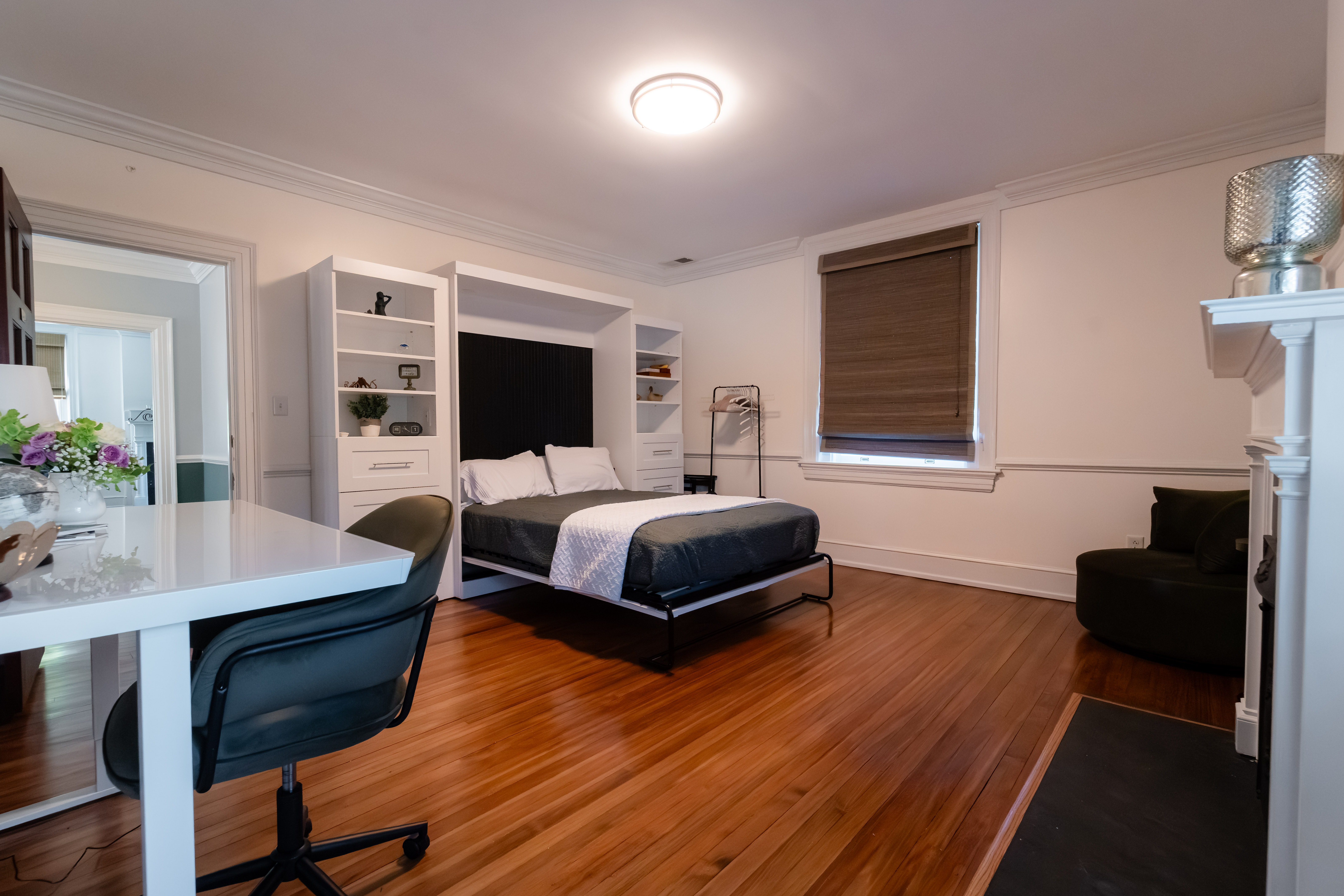 Bent Oaks Manor guest room with a Murphy bed, desk, seating, and hardwood floors.
