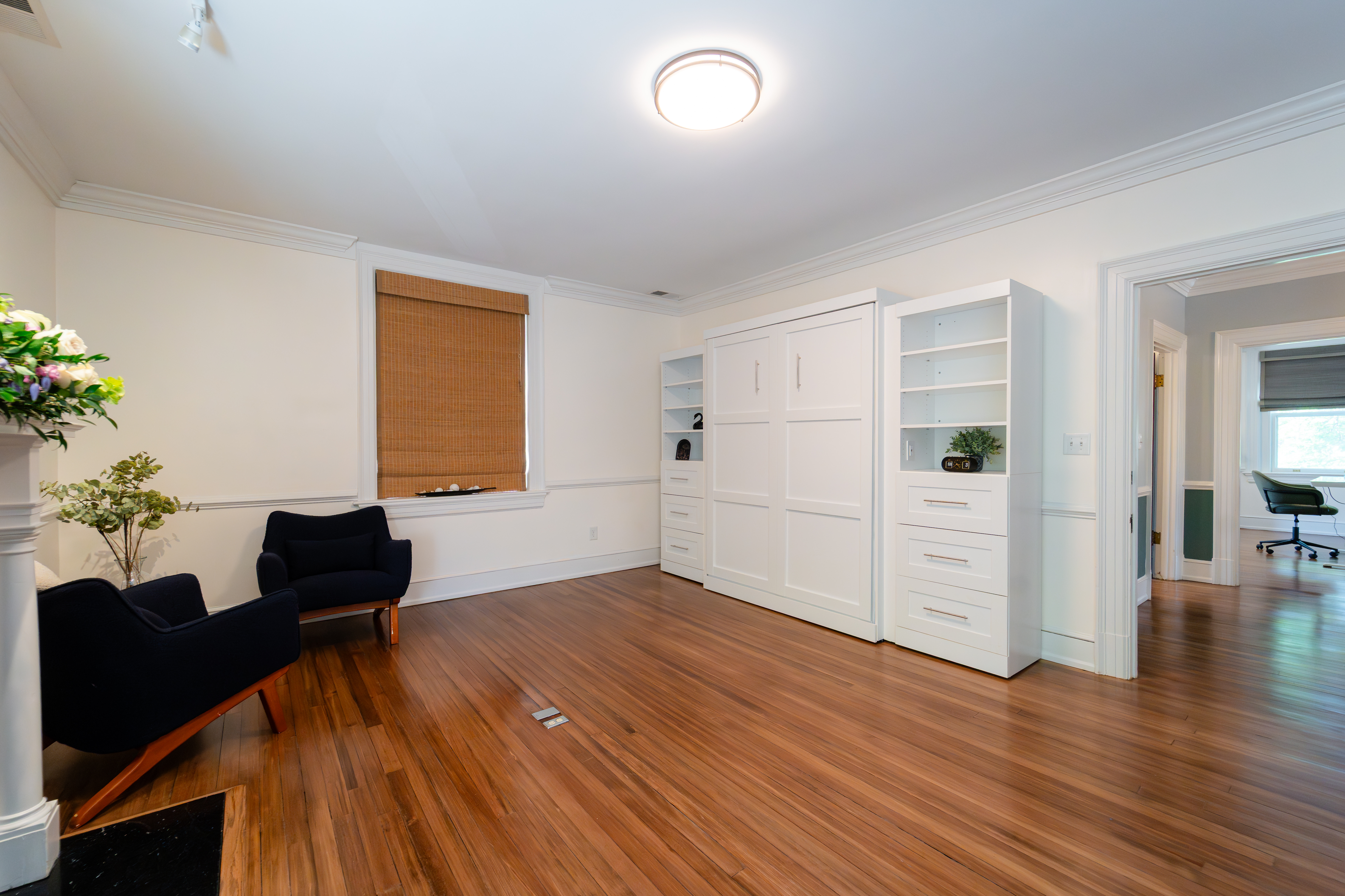 Bright Bent Oaks Manor room with hardwood floors, built-in shelving, lounge chairs, and an adjoining doorway
