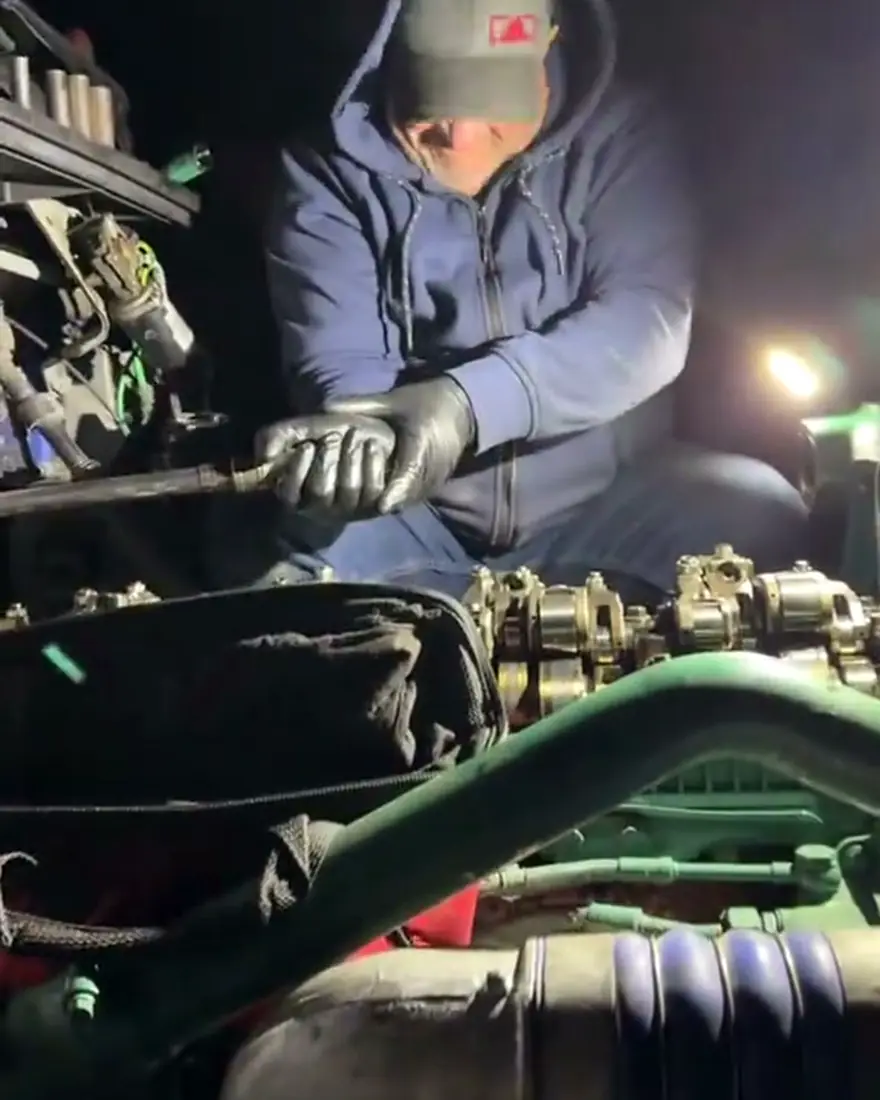 Mecánico trabajando de noche en el motor de un camión