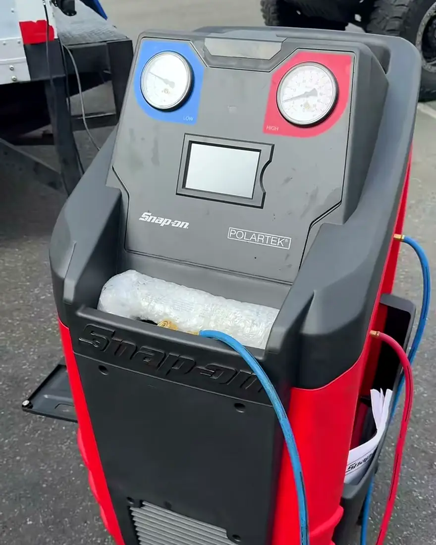 Máquina de recuperación y carga de aire acondicionado junto a un camión
