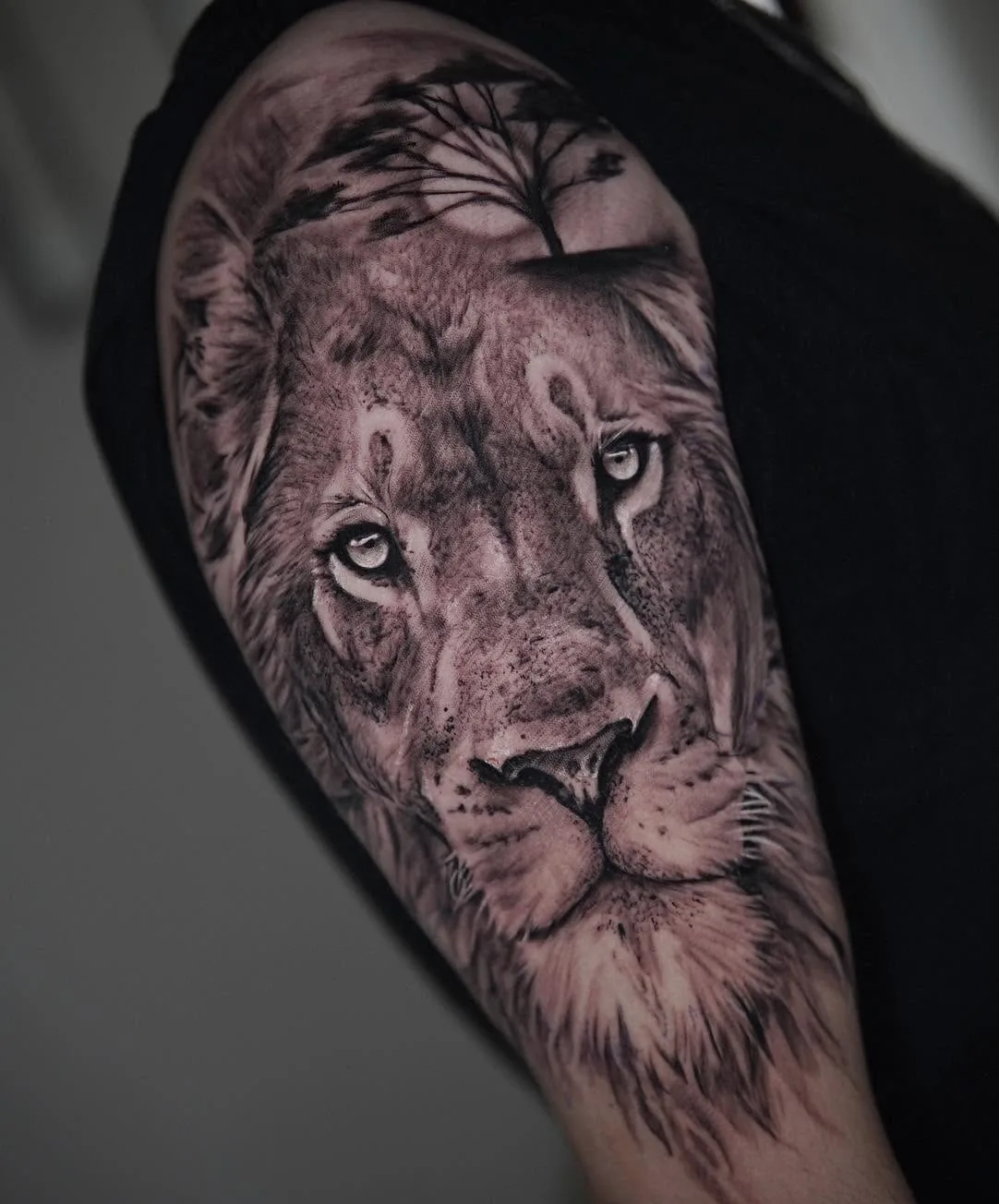 Tatuaje realista de un león con paisaje, en black and grey