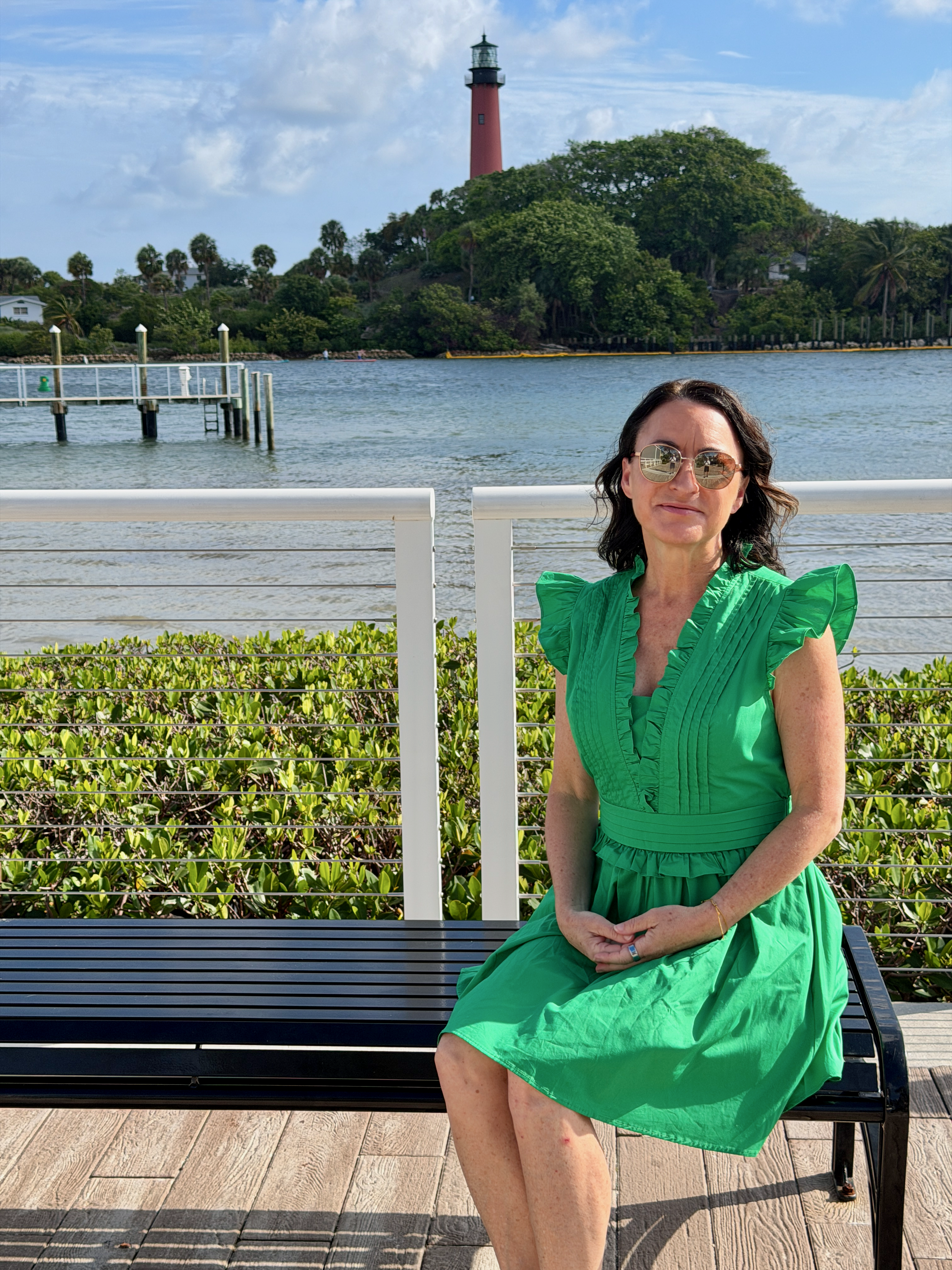 Kristin seated by the water, lighthouse behind