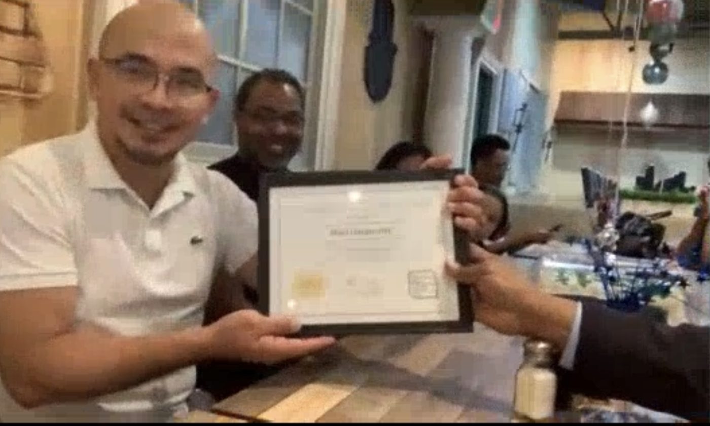 A graduate receives his framed certificate at the graduation dinner