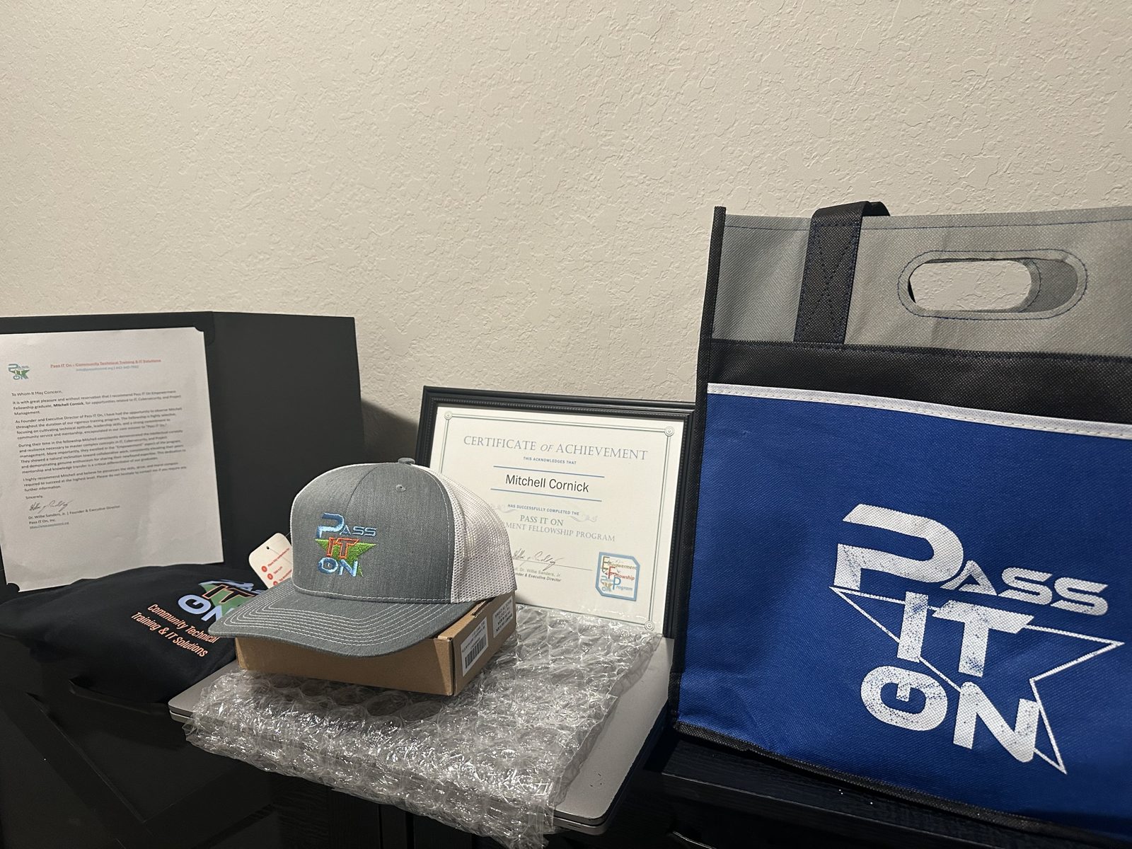 A Pass It On graduate kit: letter of recommendation, certificate, embroidered cap, shirt and bag