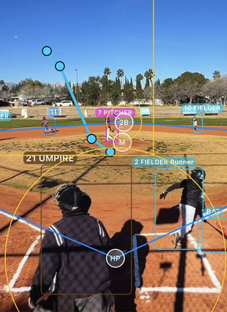 A real game seen from the backstop phone, with Pocket Blue’s tracking overlay marking the pitcher, fielders, runner, umpire and the ball’s path.