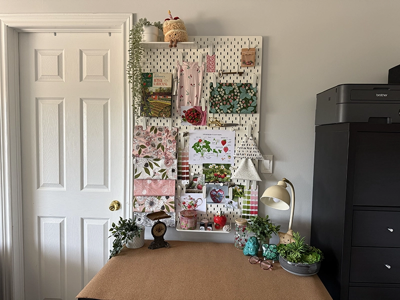 Creative workspace with a pegboard inspiration board showcasing artwork, patterns, colors, and collected inspiration for a surface pattern design collection.