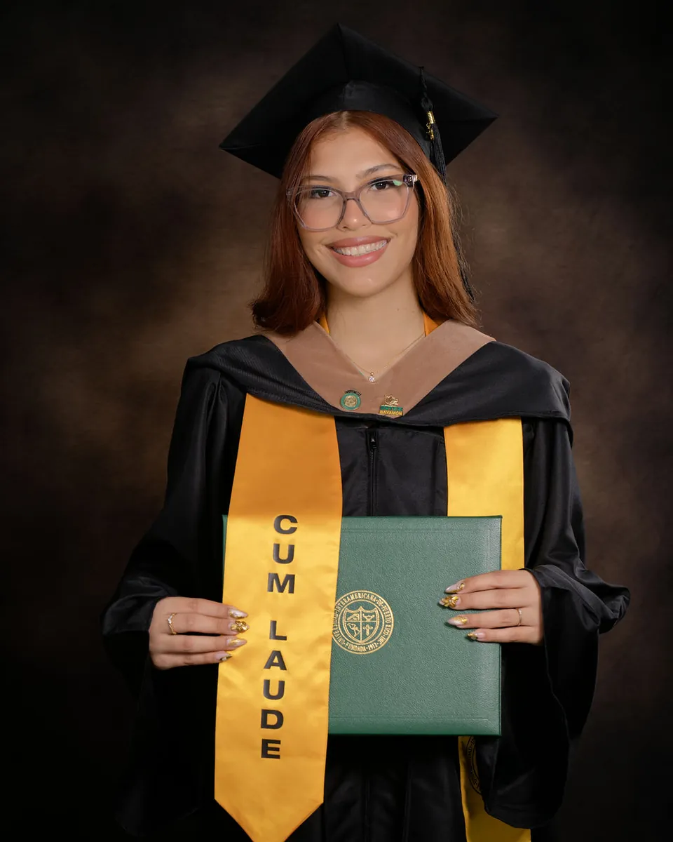 Retrato de graduada con toga, birrete, estola dorada Cum Laude y diploma verde sobre fondo marrón de estudio