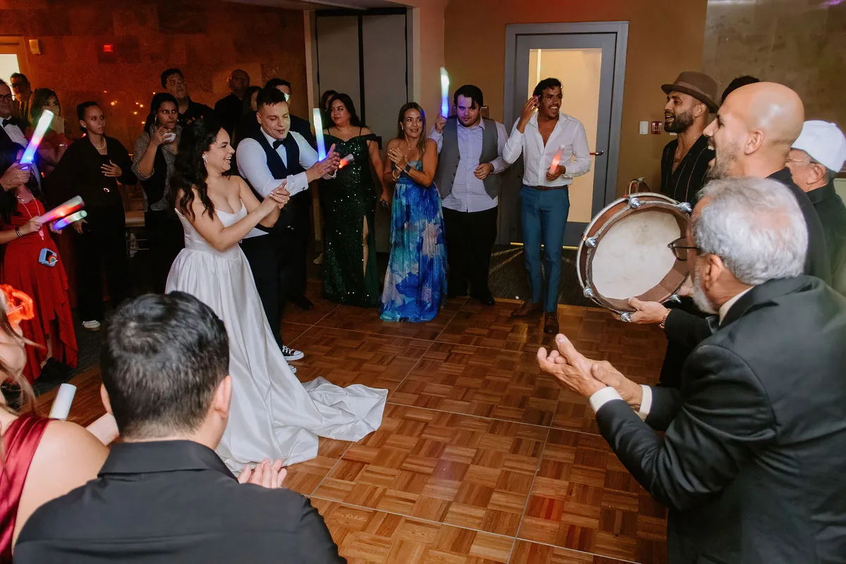 Novios bailando rodeados de músicos de plena con panderos y los invitados