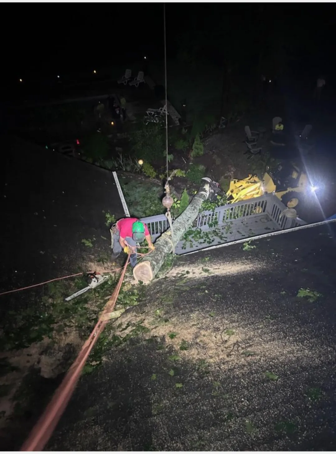 Nighttime crane extraction of storm-shattered timber from roofline