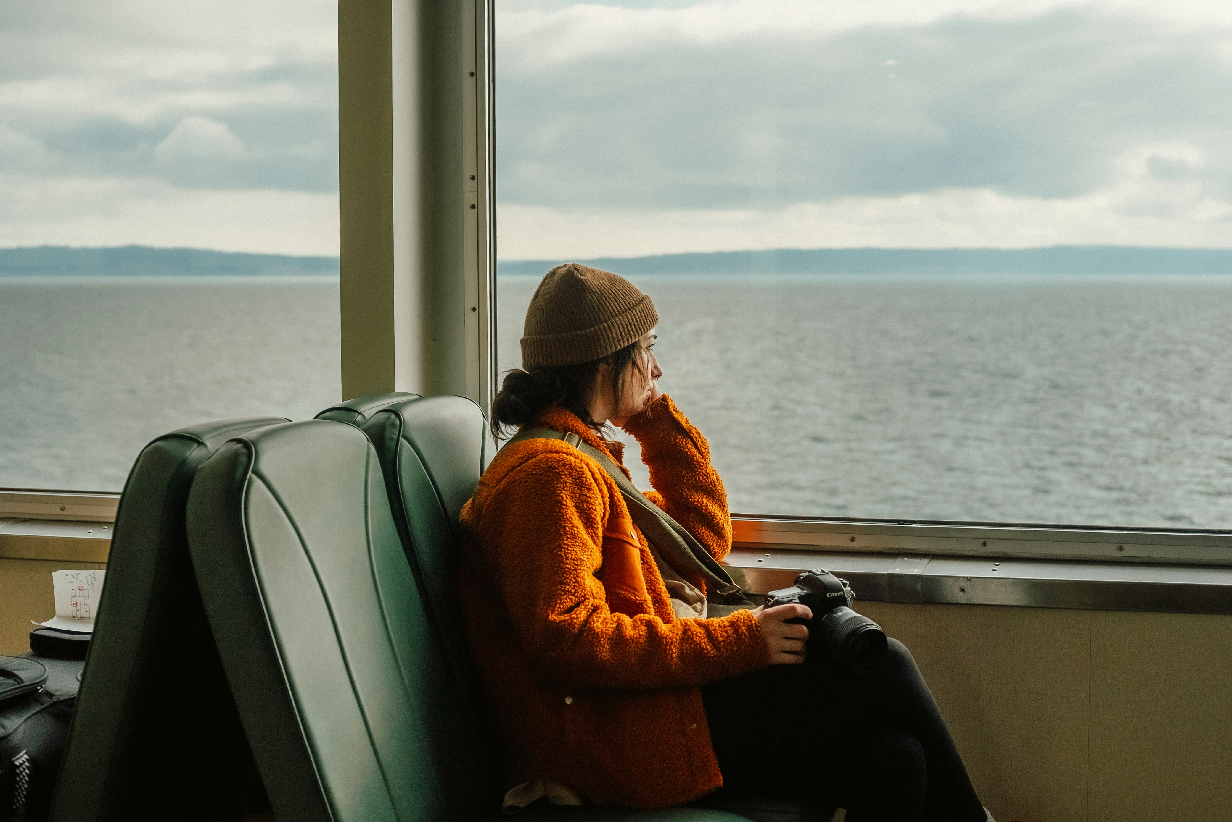 Woman travelling alone on a ferry looking through a window out to sea