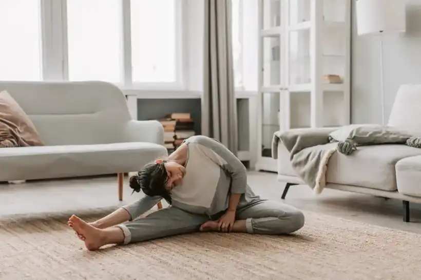A woman doing a gentle stretch on the rug in her living room