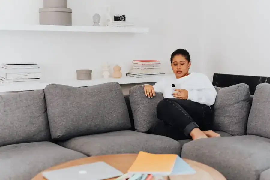 A mom relaxing on her couch at home, checking in on her phone