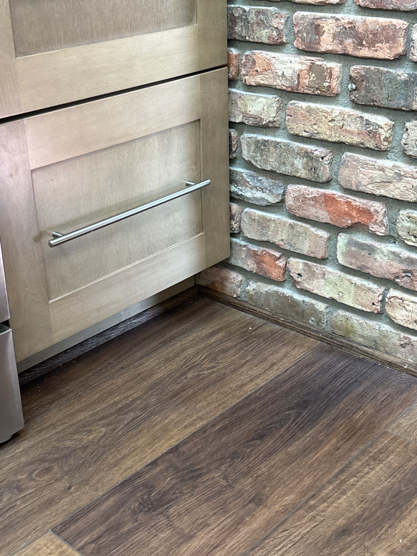 Kitchen flooring beside an exposed brick wall