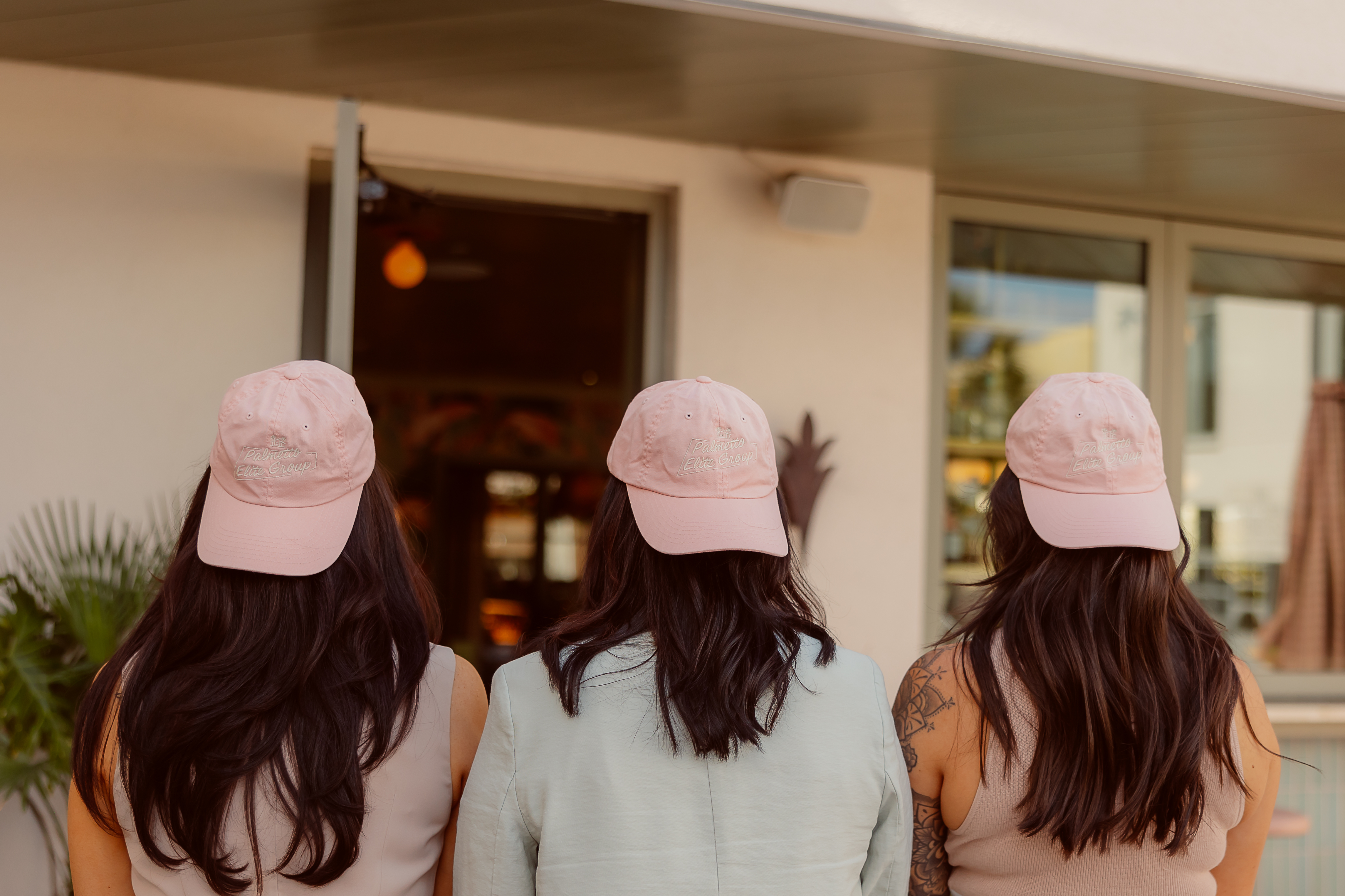 Haley Ebersole, Amy Nienstedt, and Lynnmarie Solon of Palmetto Elite Group wearing branded pink hats
