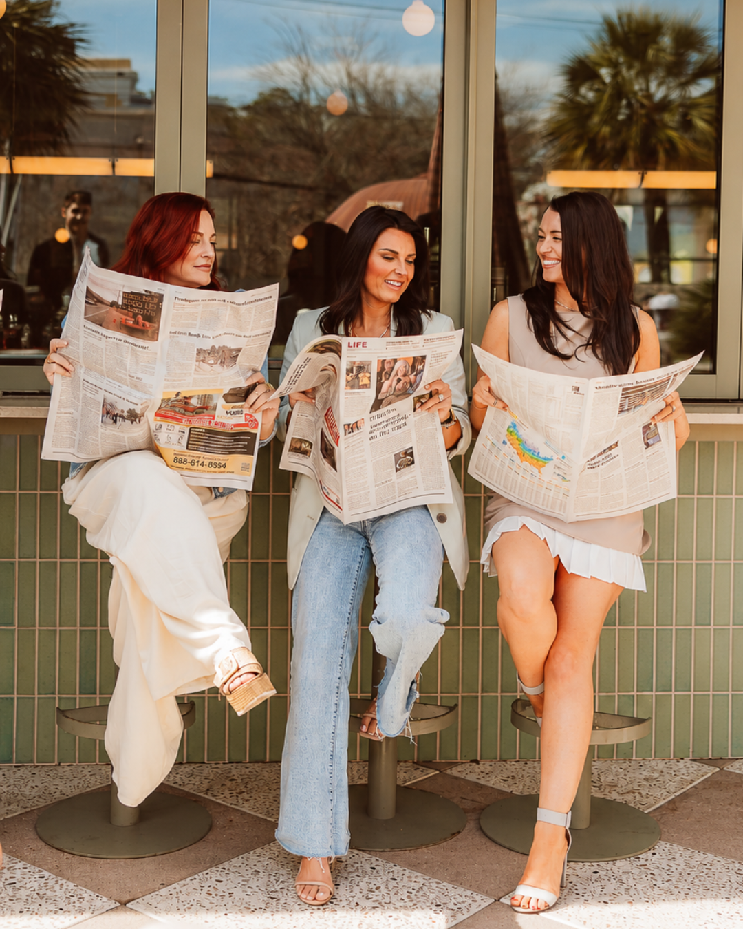 Haley Ebersole, Amy Nienstedt, and Lynnmarie Solon of Palmetto Elite Group reading a newspaper together