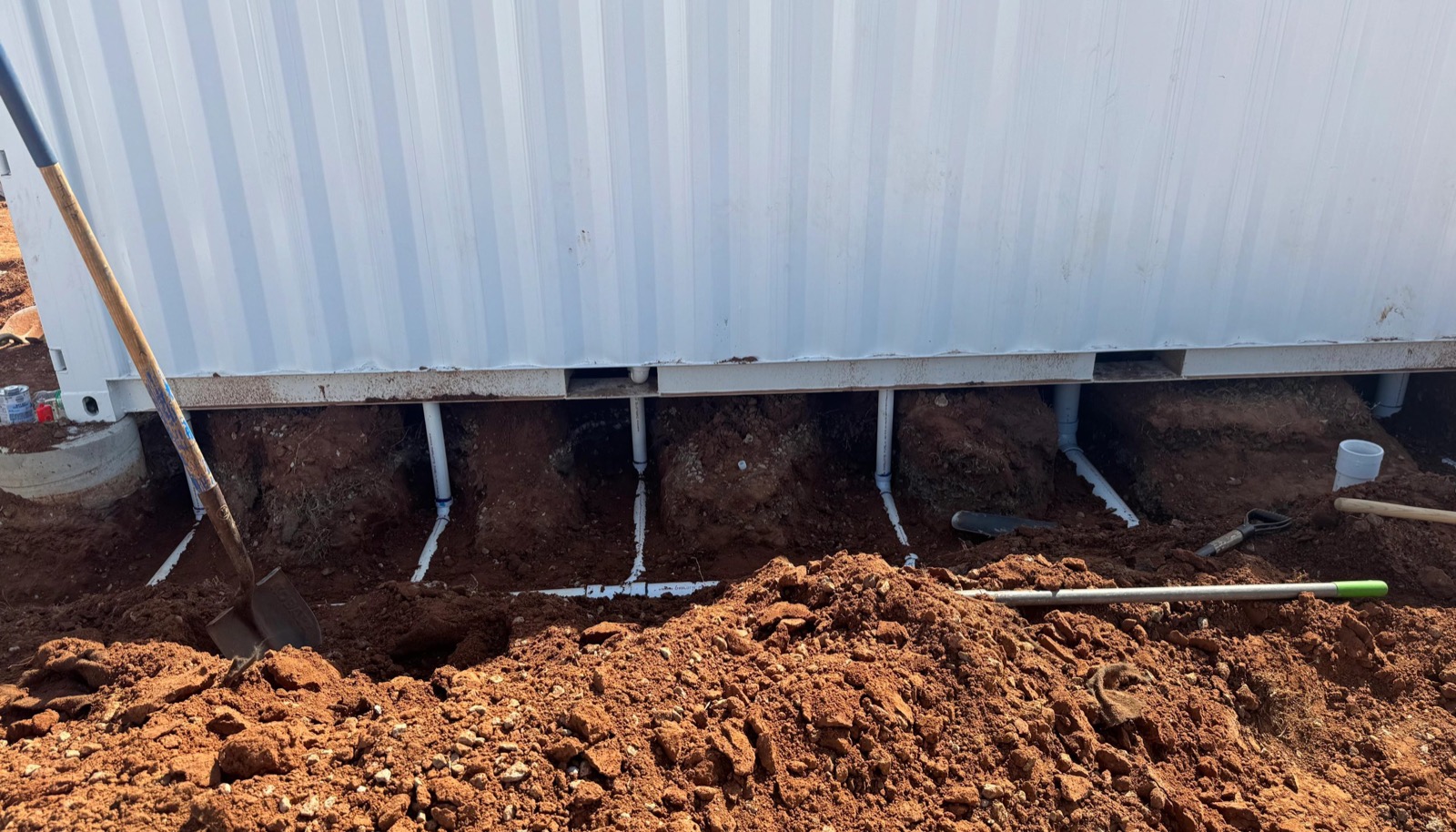 Plumbing rough-in on red dirt during a commercial project near Fort Smith
