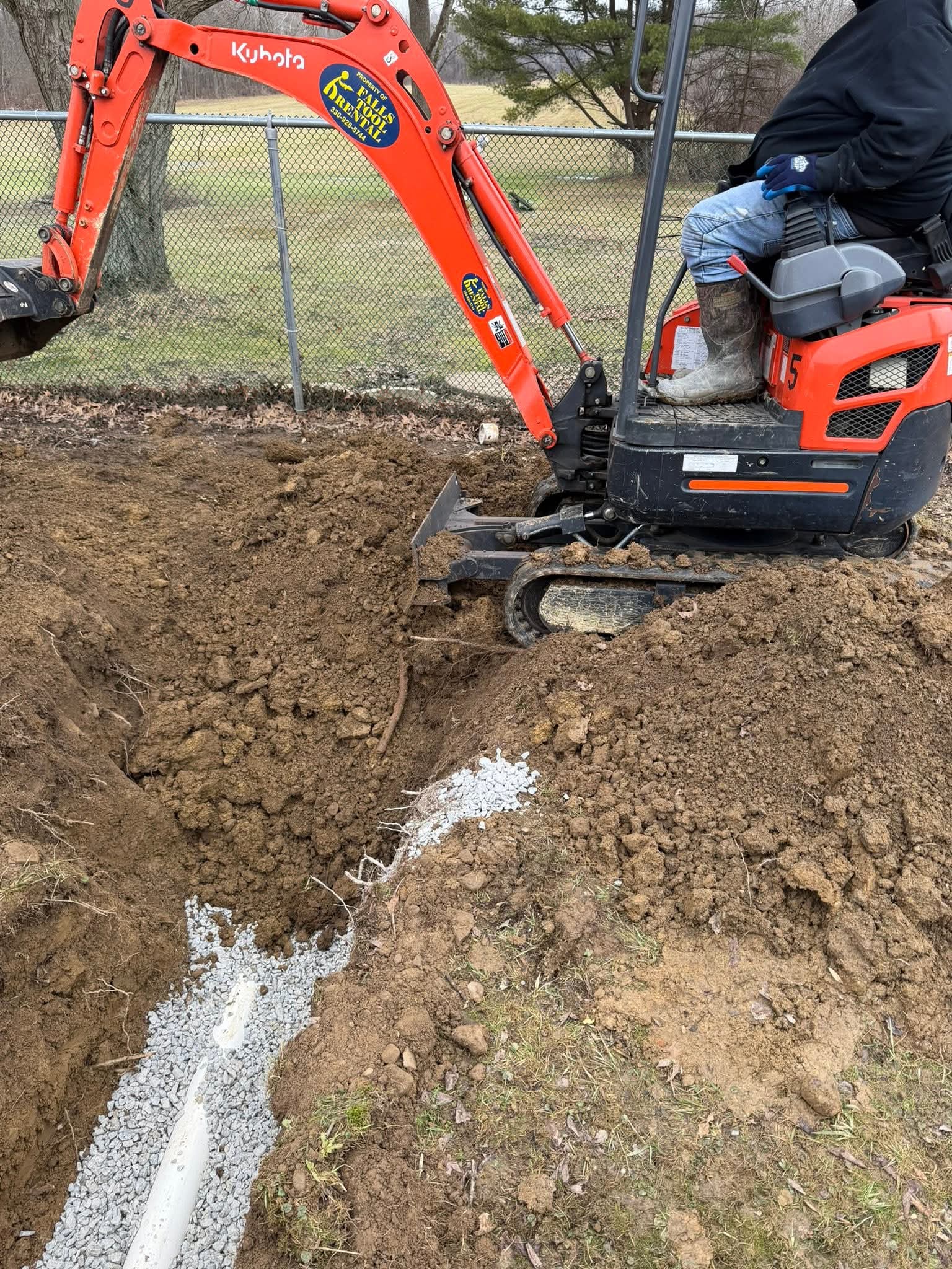 Excavator performing trenching operations for underground sewer line work