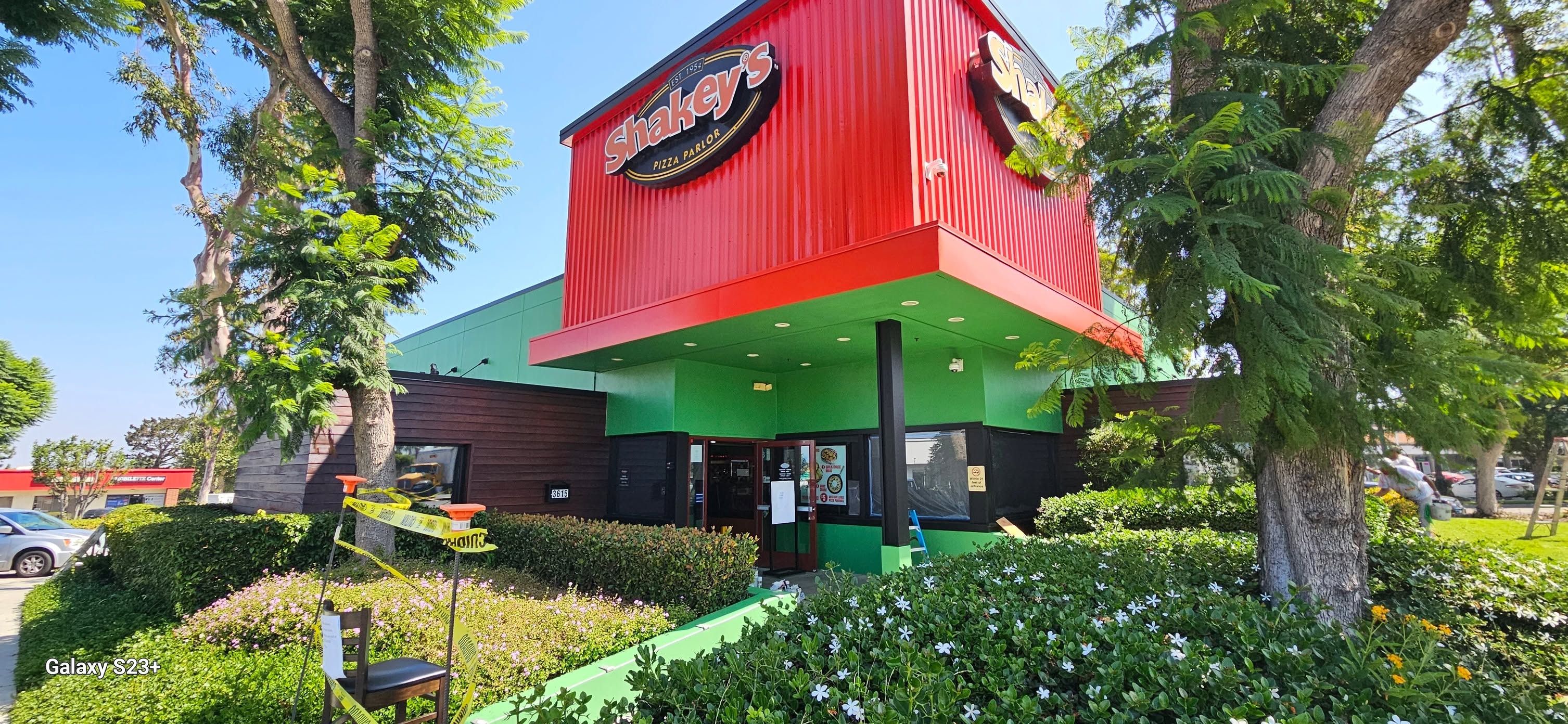 After: the same storefront in vivid brand red with a bright green soffit and freshly finished entry columns.