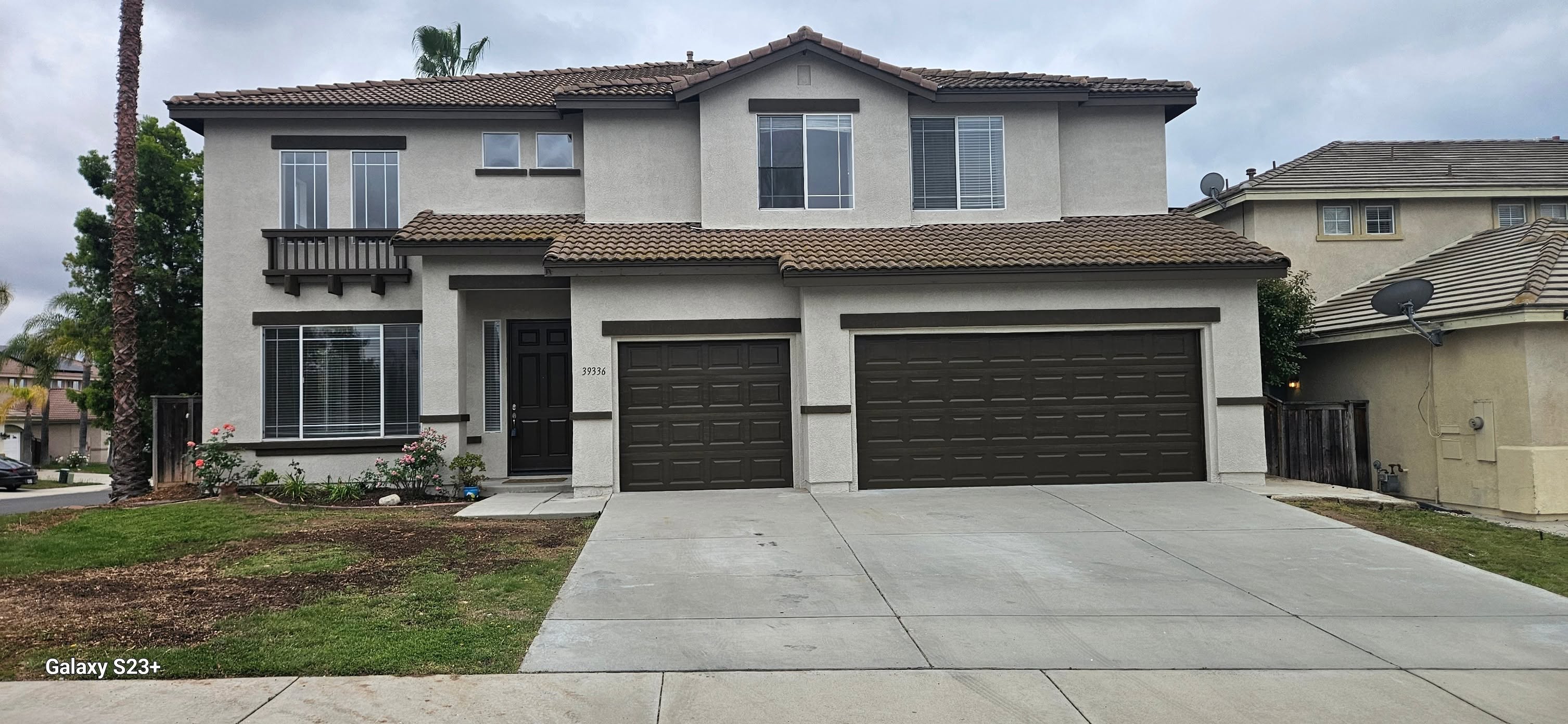 After: the same home in crisp warm white with deep espresso trim, balcony and garage doors.