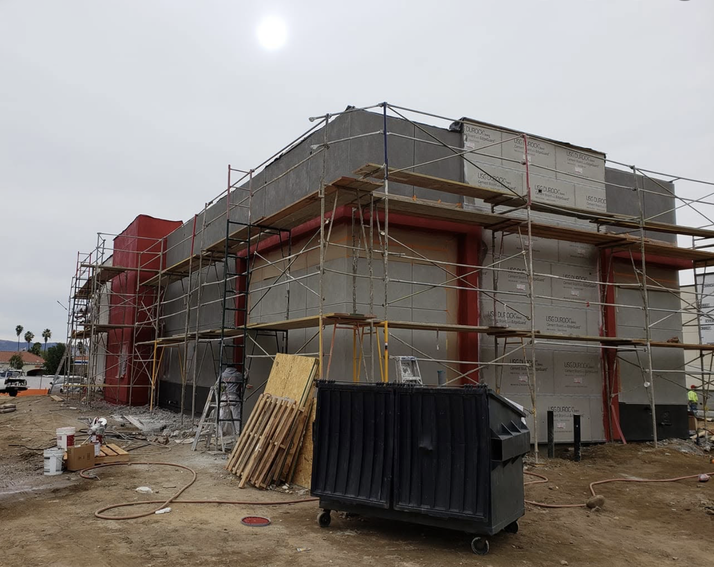 Scaffolding along a commercial building elevation mid-coating on an Upper Room job site.