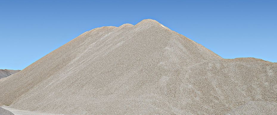 Large stockpile of sand and gravel under a clear blue sky, ready for delivery