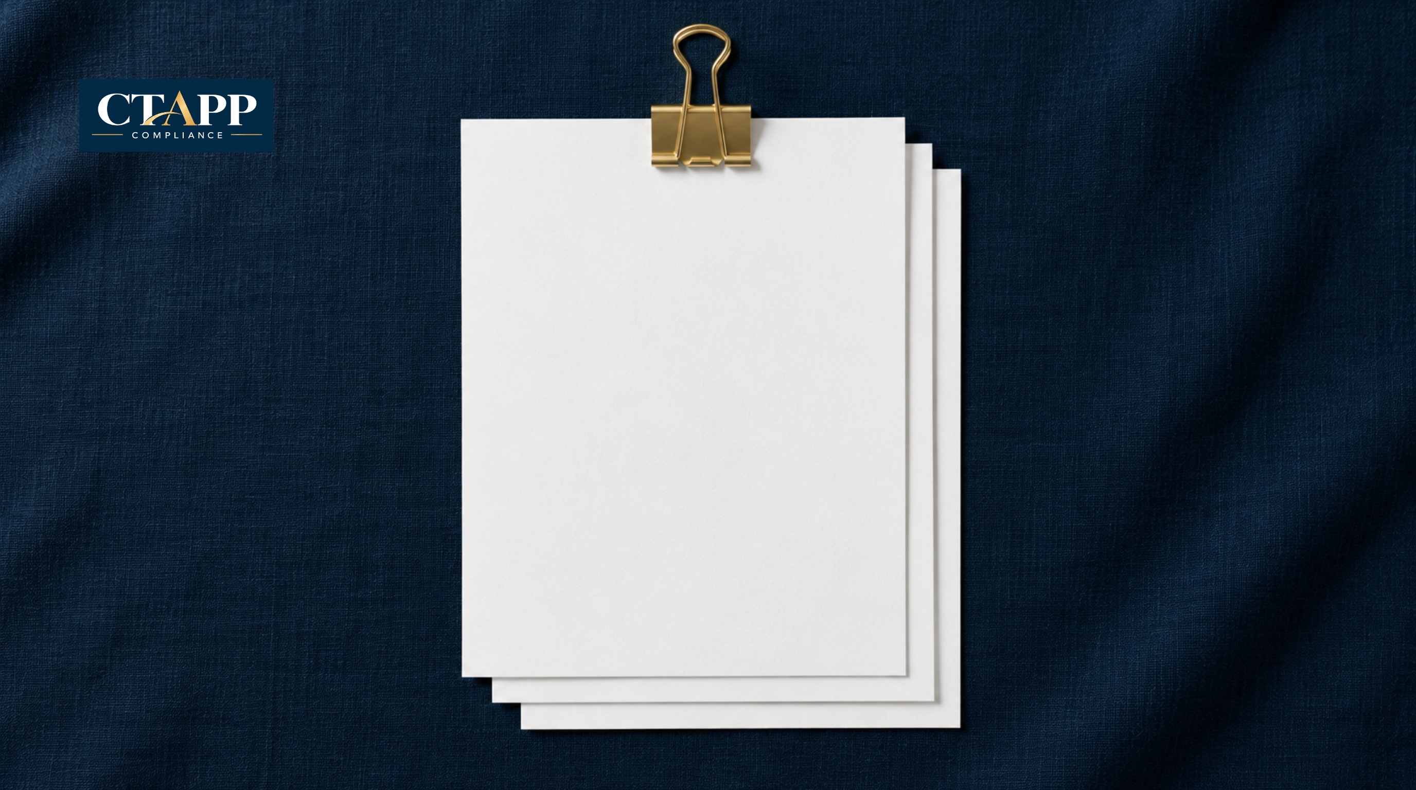 Three blank pages joined by a gold binder clip on navy linen Three blank pages joined by a gold binder clip on navy linen