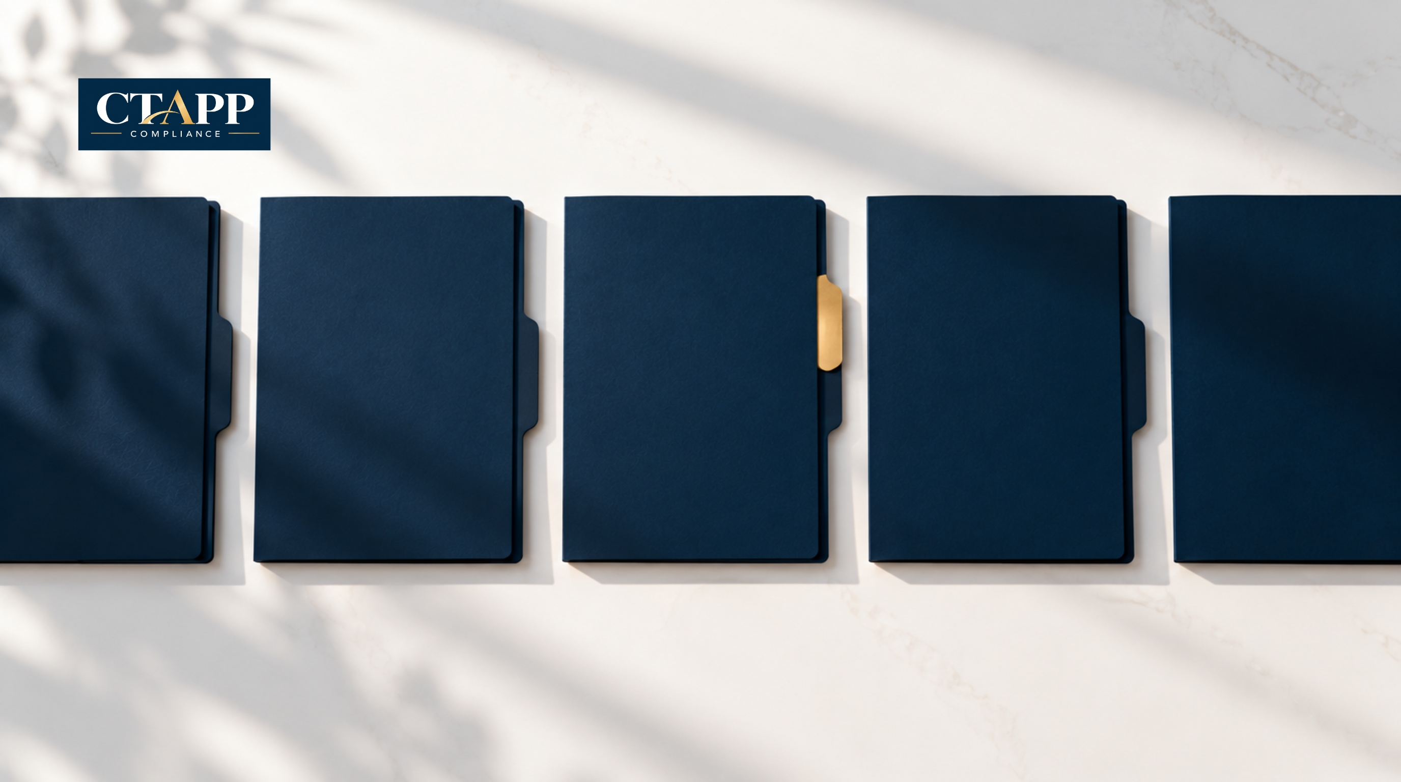 Row of navy folders with one gold tab raised on a white surface Row of navy folders with one gold tab raised on a white surface