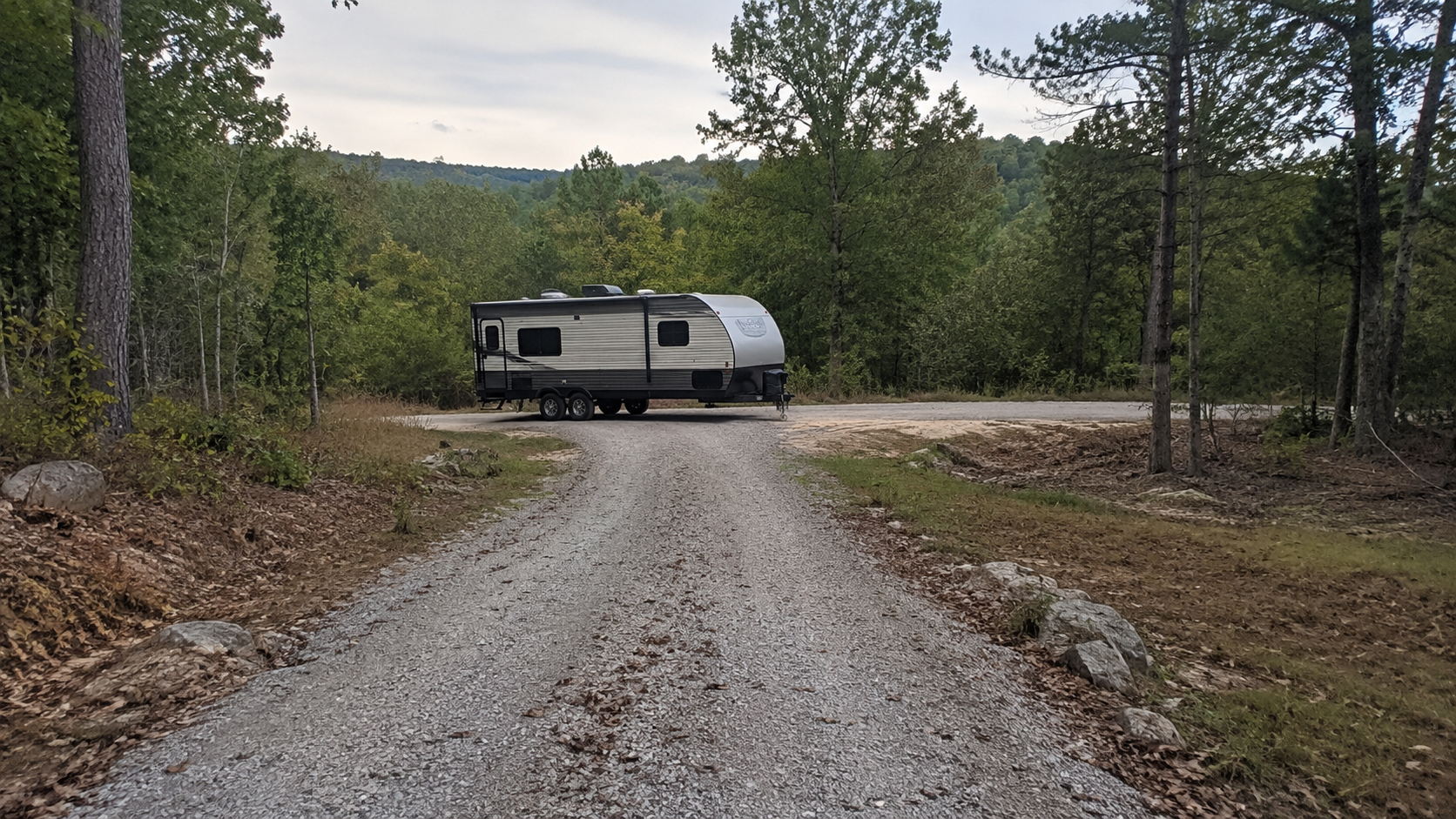 Travel trailer evaluating gravel road access to rural wooded land Travel trailer evaluating gravel road access to rural wooded land