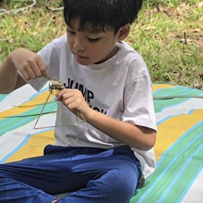A child weaving with coconut leaves on a mat