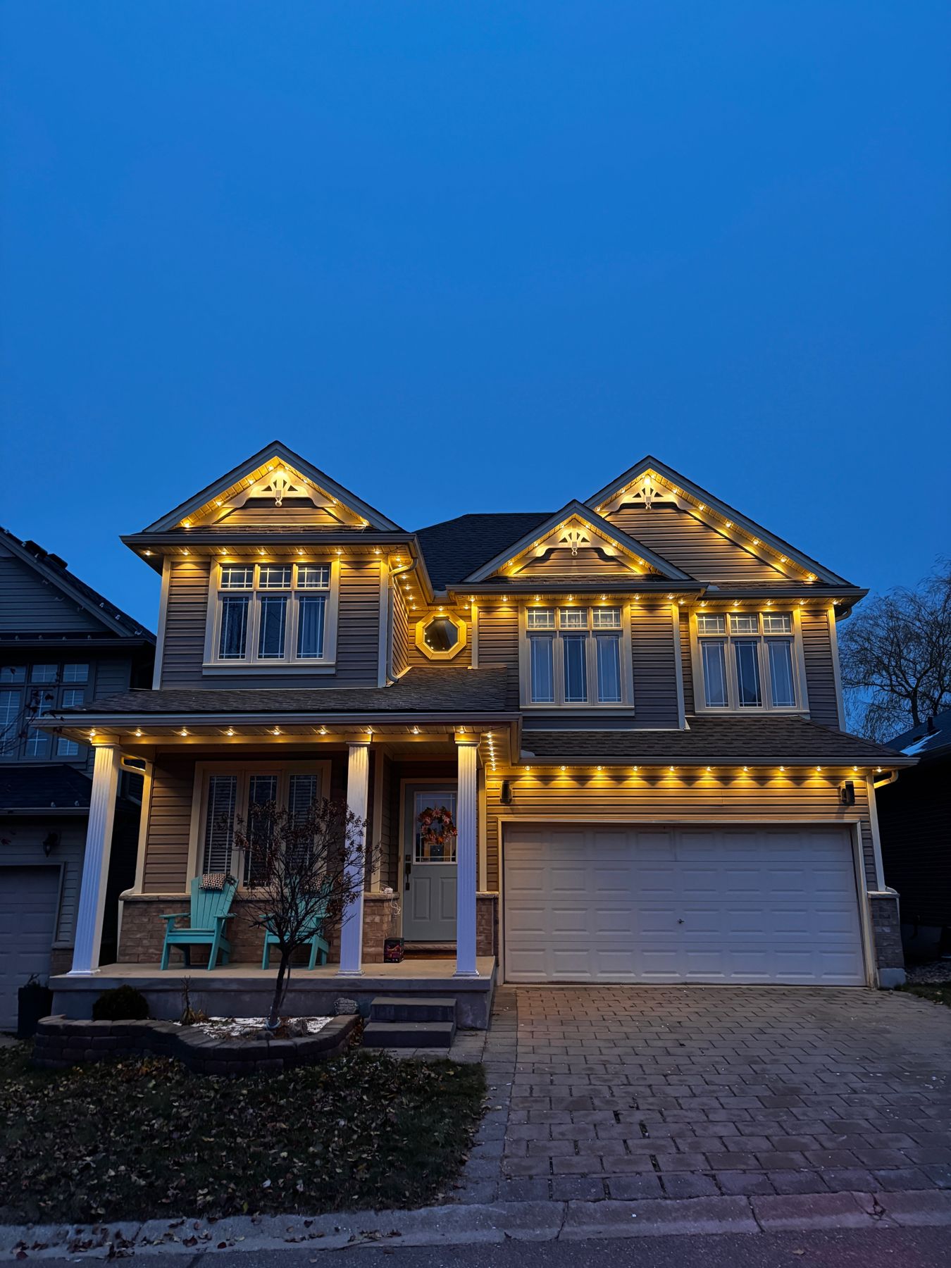 Warm white permanent roofline lights on a two-storey home in Barrie