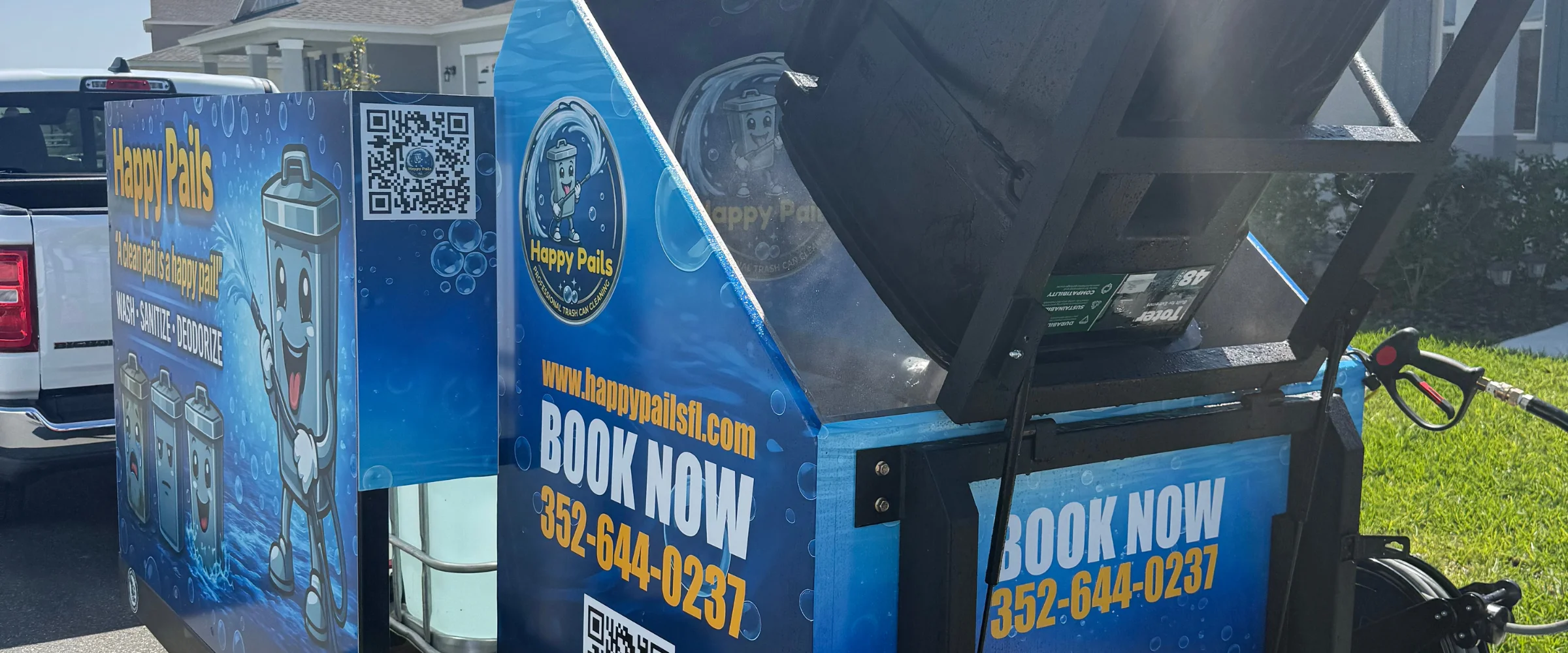 A mobile Happy Pails professional trash can cleaning system with a pressure washer and a can being cleaned. A mobile Happy Pails professional trash can cleaning system with a pressure washer and a can being cleaned.