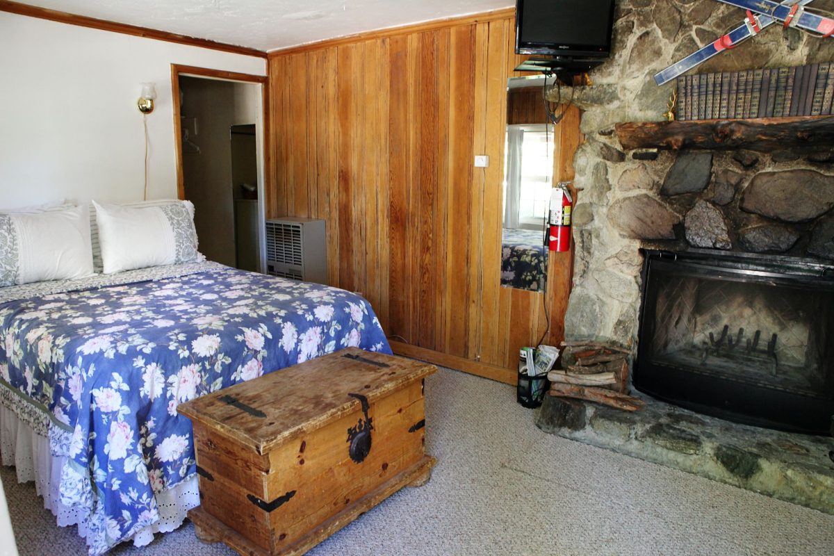 A cabin bedroom with a quilt and stone fireplace
