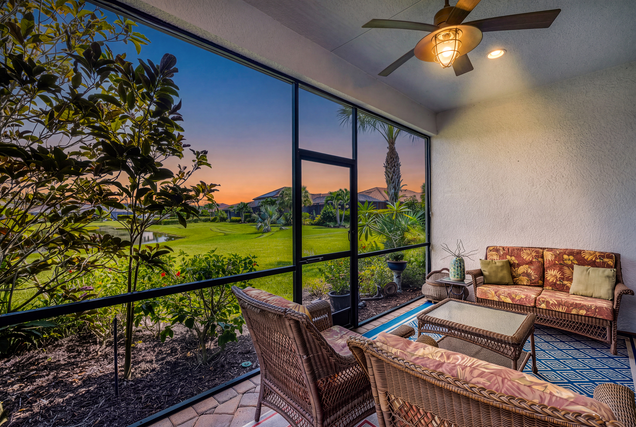 Screened lanai at sunset overlooking the lake at 10852 Essex Square Blvd in Hampton Park at Gateway, Fort Myers