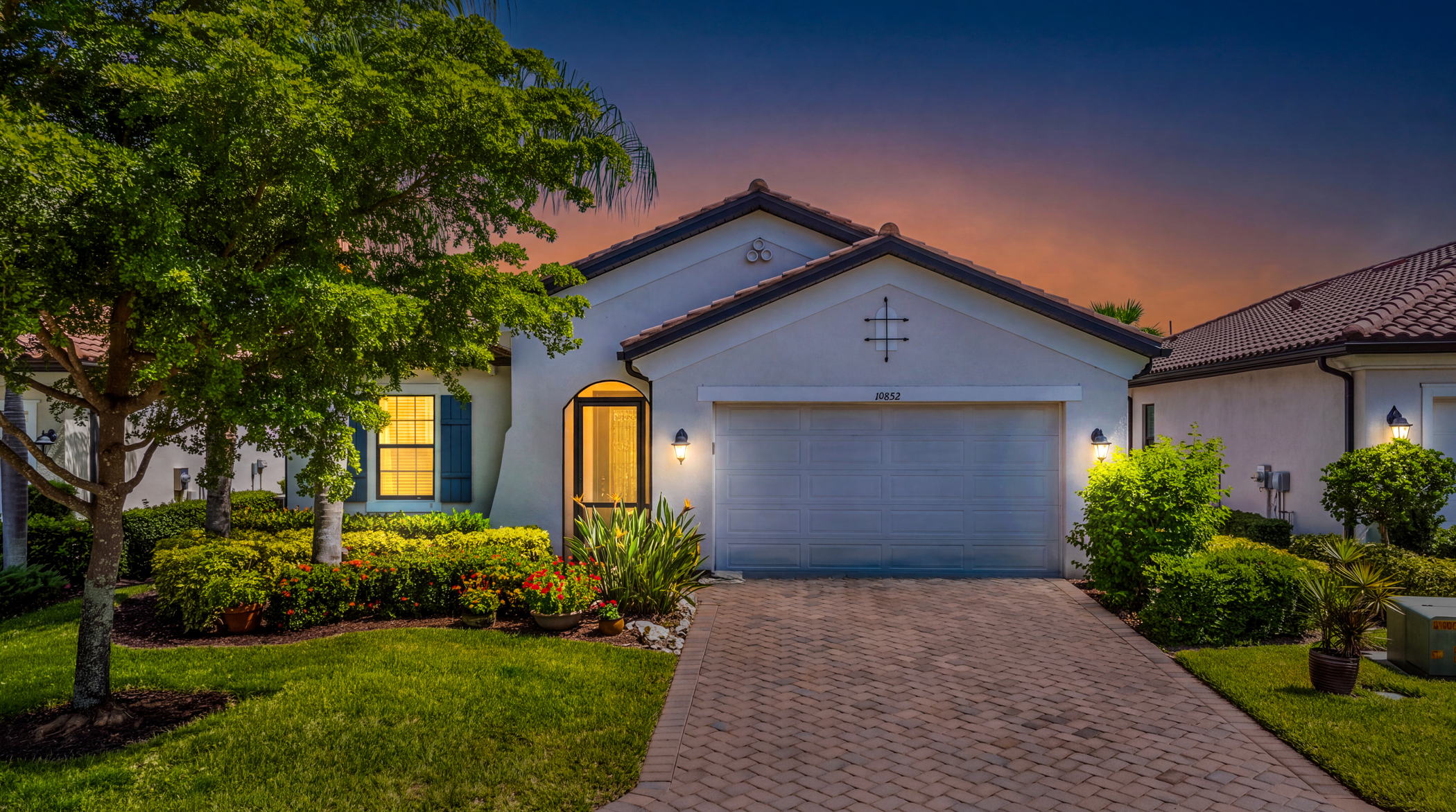 Front exterior at twilight of 10852 Essex Square Blvd, a WCI built lakefront home in Hampton Park at Gateway, Fort Myers FL
