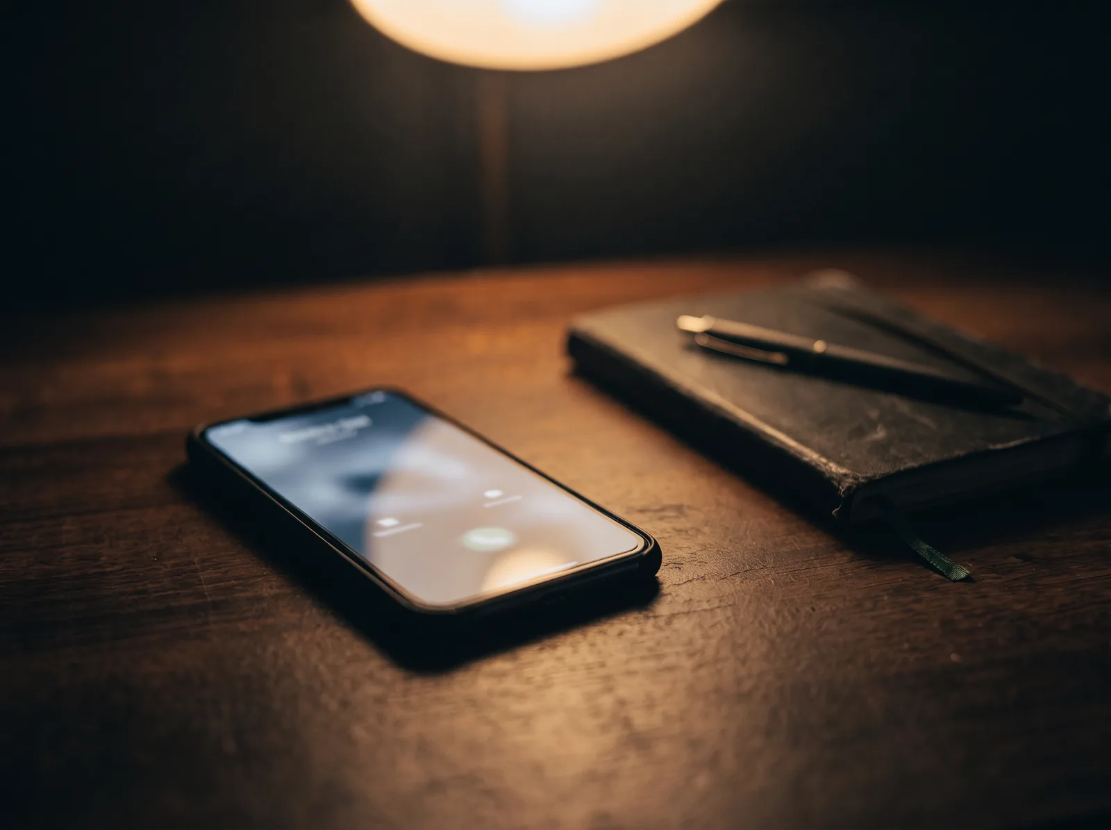 A phone on a dark desk lighting up with an incoming call