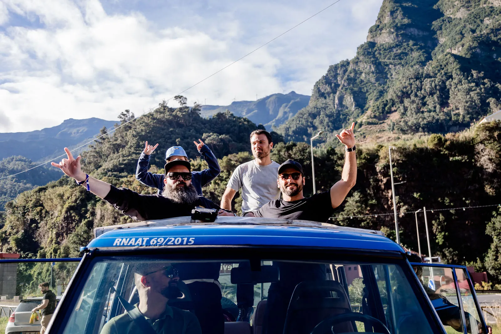 Founders cheering from a jeep with Madeira's mountains behind them