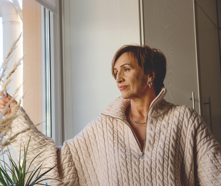 Reflective woman looking through a window while considering family relationship patterns