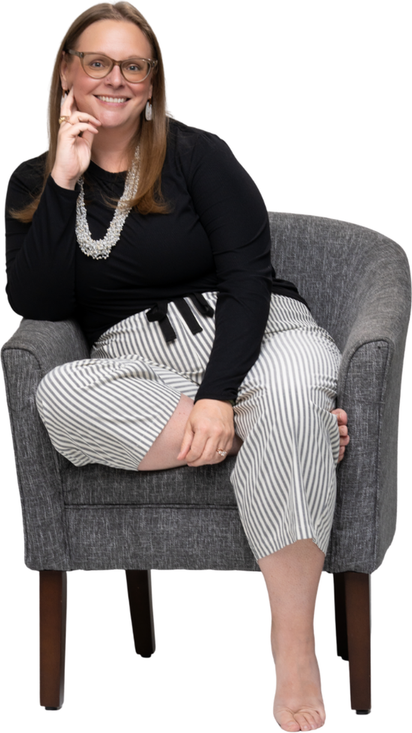Tara sitting in an armchair, smiling, hand resting against her cheek