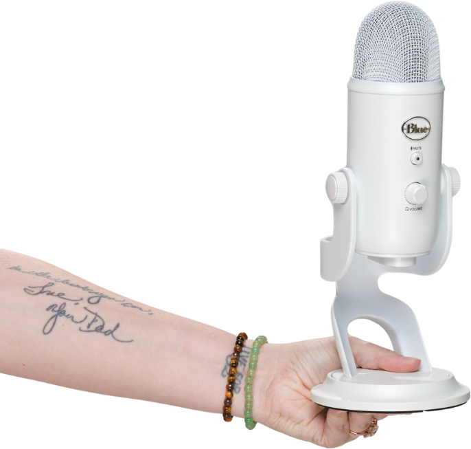 A hand holding up a white Blue microphone