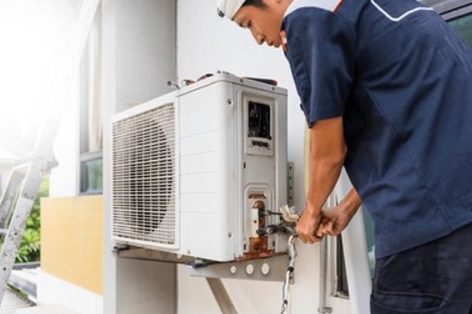 Licensed HVAC technician connecting refrigerant lines during a professional AC installation