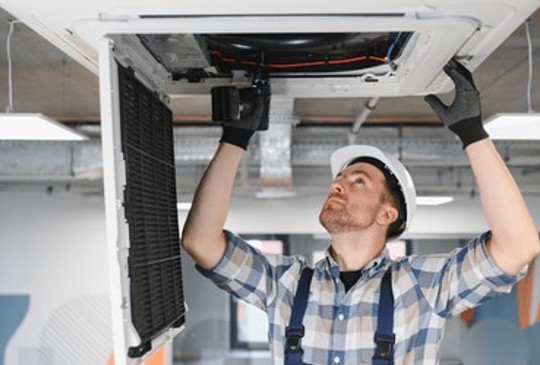 Licensed HVAC contractor servicing a ceiling-mounted air handler during an indoor inspection