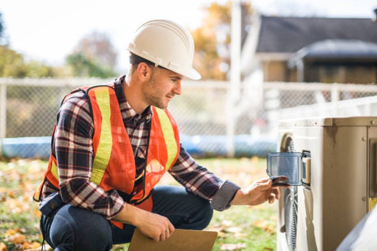 Licensed HVAC contractor checking outdoor unit connections during a fall maintenance visit