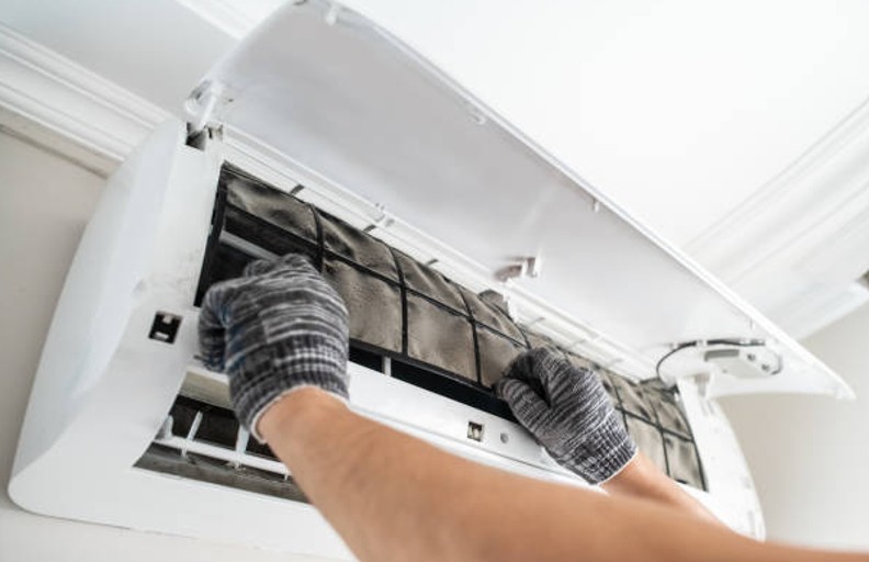 Technician removing a clogged air filter during a home air quality solutions maintenance visit Technician removing a clogged air filter during a home air quality solutions maintenance visit