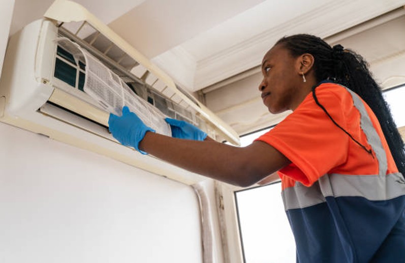 Technician inspecting indoor AC unit during an AC replacement cost evaluation in an Alabama home Technician inspecting indoor AC unit during an AC replacement cost evaluation in an Alabama home