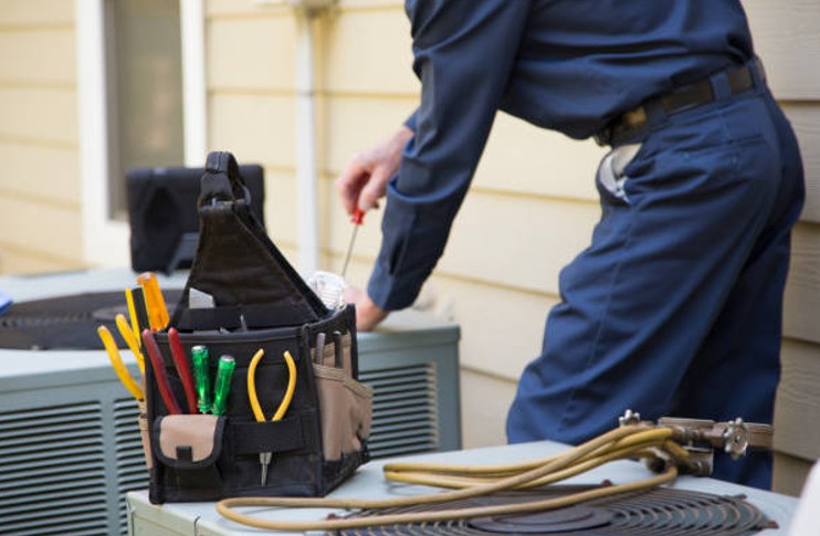 HVAC technician servicing an outdoor condenser unit during a scheduled preventive HVAC maintenance appointment HVAC technician servicing an outdoor condenser unit during a scheduled preventive HVAC maintenance appointment